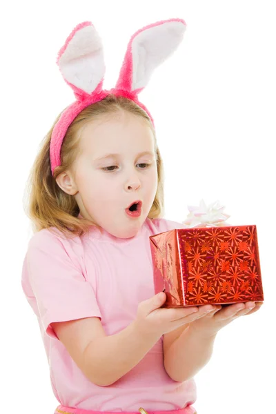 Holčička s růžové uši zajíčka s dárkem na bílém pozadí. — Stock fotografie