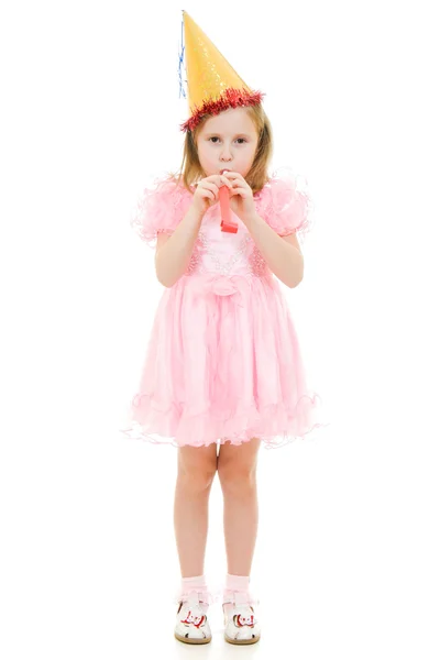 Een meisje in een roze jurk en hoed waait in de pijp op een witte achtergrond. — Stockfoto