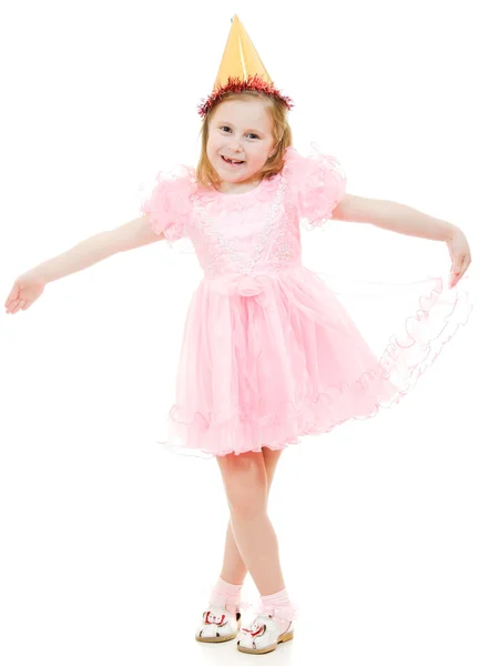 A lány egy rózsaszín ruhában és kalapban táncol egy fehér háttér. — Stock Fotó