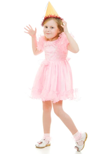 En flicka i en rosa klänning och hatt danser på en vit bakgrund. — Stockfoto