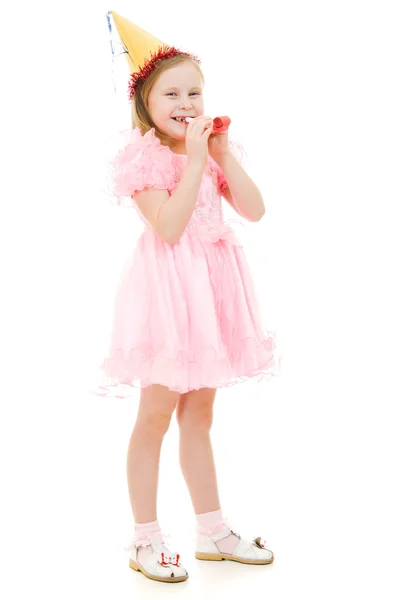 Een meisje in een roze jurk en hoed waait in de pijp op een witte achtergrond. — Stockfoto