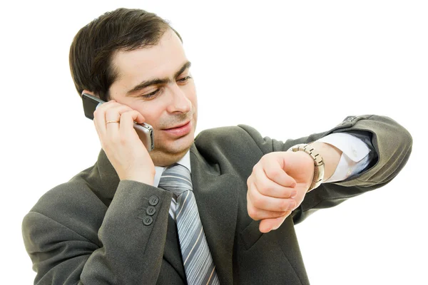 Podnikatel při pohledu na hodinky a mluví po telefonu na bílém pozadí — Stock fotografie