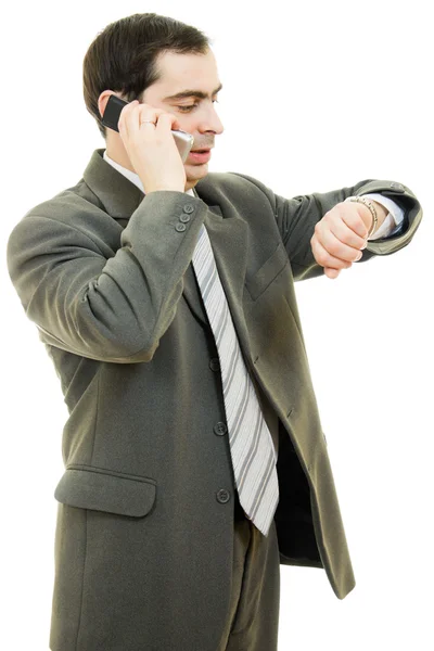 Uomo d'affari che guarda il suo orologio e parla al telefono su un retro bianco — Foto Stock