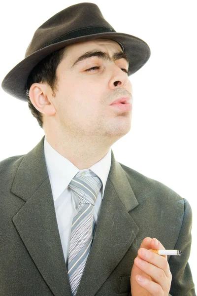 Un homme d'affaires dans un chapeau fume sur un fond blanc . — Photo