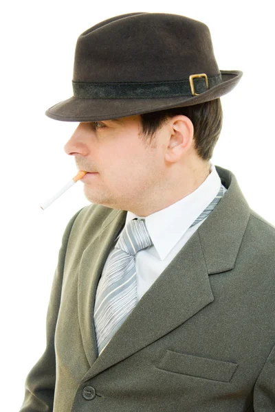 Un uomo d'affari con un cappello fuma su uno sfondo bianco . — Foto Stock