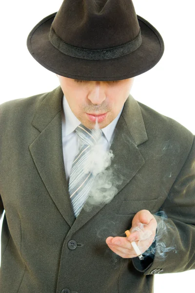 Een zakenman in een hoed rookt op een witte achtergrond. — Stockfoto