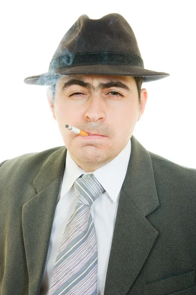 Un hombre de negocios con sombrero fuma sobre un fondo blanco . — Foto de Stock
