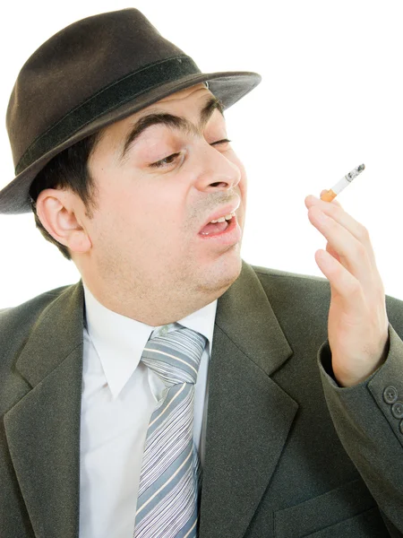 Un uomo d'affari con un cappello fuma su uno sfondo bianco . — Foto Stock