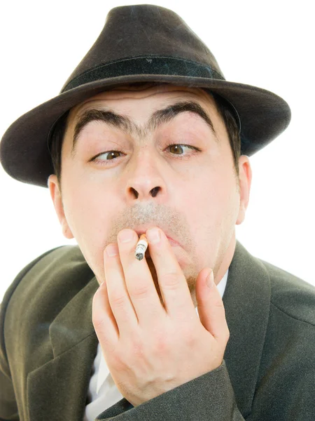 Um homem de negócios de chapéu fuma em um fundo branco . — Fotografia de Stock