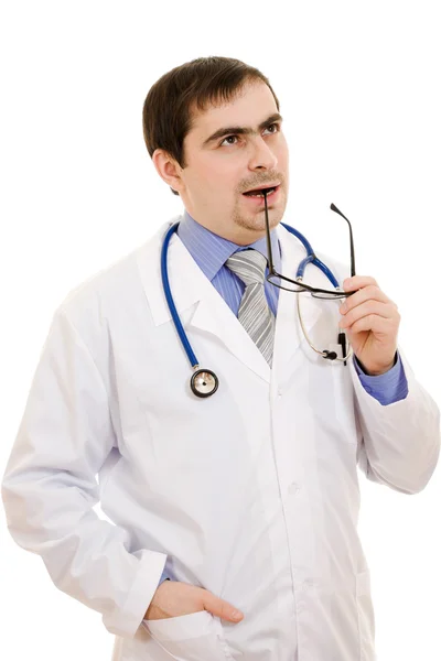 Un médico con un estetoscopio y gafas pensando en un fondo blanco —  Fotos de Stock