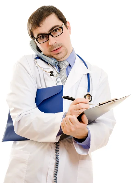 Male doctor talking on the phone and writing on the document plate on a whi — Stock Photo, Image