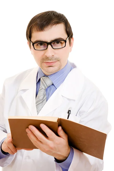 Um médico com um estetoscópio está lendo um livro sobre um fundo branco . — Fotografia de Stock