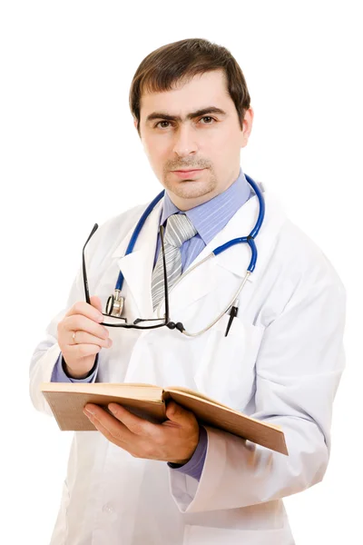 Um médico com um estetoscópio está lendo um livro sobre um fundo branco . — Fotografia de Stock
