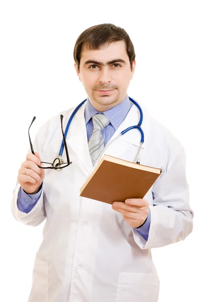 Un medico con uno stetoscopio sta leggendo un libro su sfondo bianco . — Foto Stock