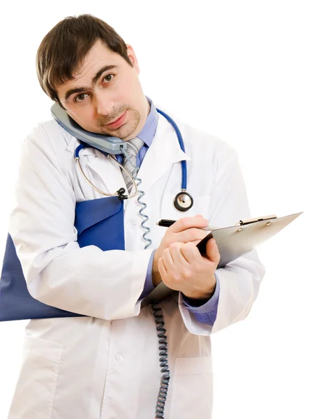 Male doctor talking on the phone and writing on the document plate on a whi Stock Image