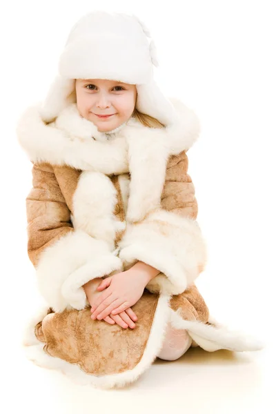 Ένα κορίτσι σε ένα γούνινο παλτό και το καπέλο που είναι χαμογελώντας σε άσπρο φόντο. — Φωτογραφία Αρχείου