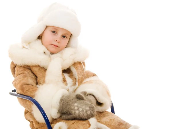 La chica en ropa de abrigo se sienta en un trineo sobre un fondo blanco . — Foto de Stock