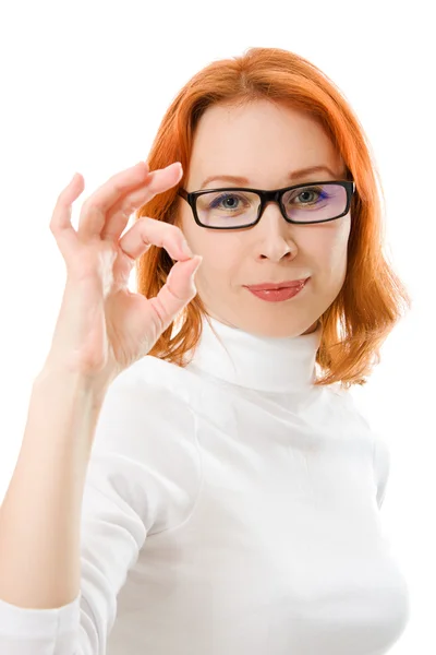 Ein schönes Mädchen mit roten Haaren und Brille zeigt auf weißem Hintergrund eine Geste, die in Ordnung ist. — Stockfoto