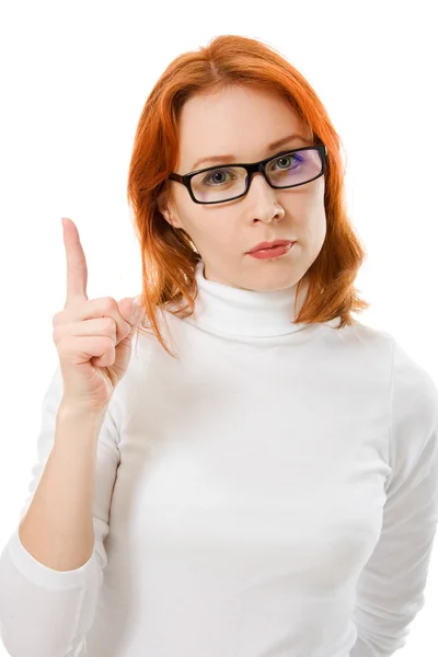 Ein schönes Mädchen mit roten Haaren und Brille zeigt mit dem Finger nach oben auf weißem Hintergrund. — Stockfoto