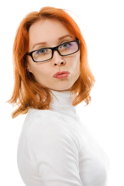 A beautiful girl with red hair wearing glasses kissing on a white background. — Stock Photo, Image