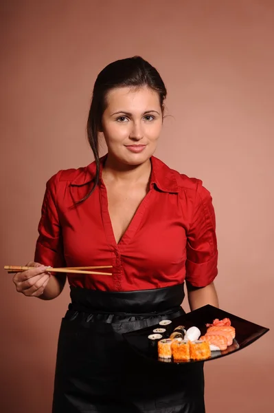 Mujer vestida de rojo con palillos y plato de sushi — Foto de Stock