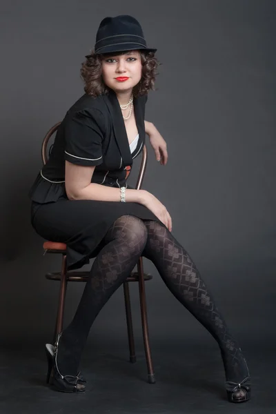 Girl in black on a chair — Stock Photo, Image