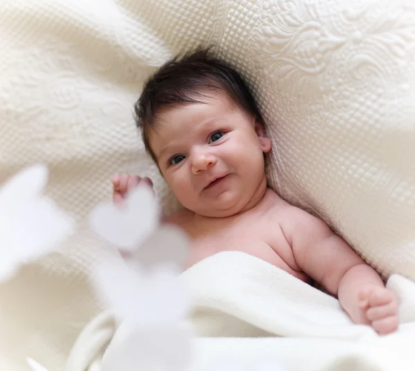 Retrato de um bebê de close-up deitado na cama com brinquedo móvel — Fotografia de Stock