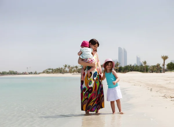 Mamma och hennes lilla döttrar på stranden — Stockfoto