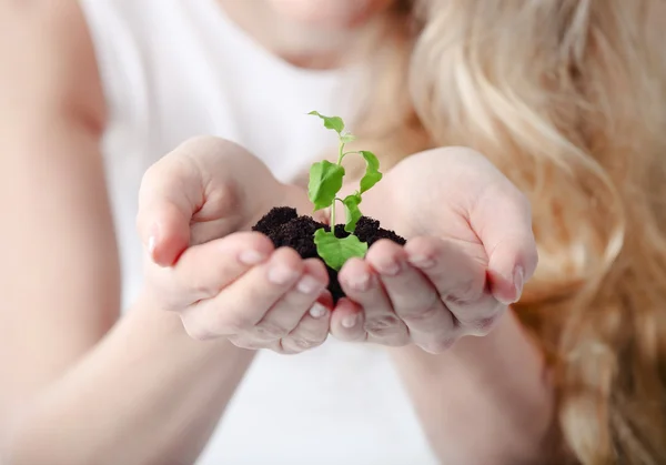 Young woman holding young plant in her hands — Stock Photo, Image