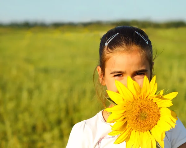 Portrét roztomilá holčička, schovává se za slunečnice — Stock fotografie