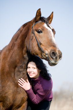 Young girl and bay horse in field. clipart