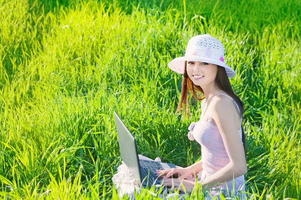 Sonríe chica usando el ordenador portátil en prado verde —  Fotos de Stock