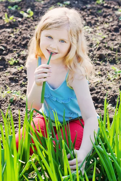 Kislány zöld hagymát eszik — Stock Fotó