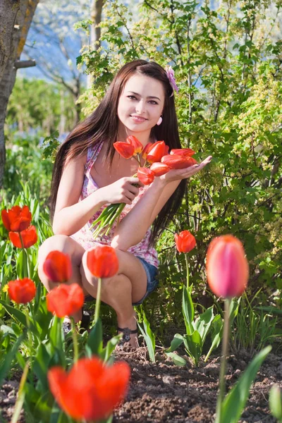 Όμορφο κορίτσι με τα λουλούδια στον κήπο — Φωτογραφία Αρχείου
