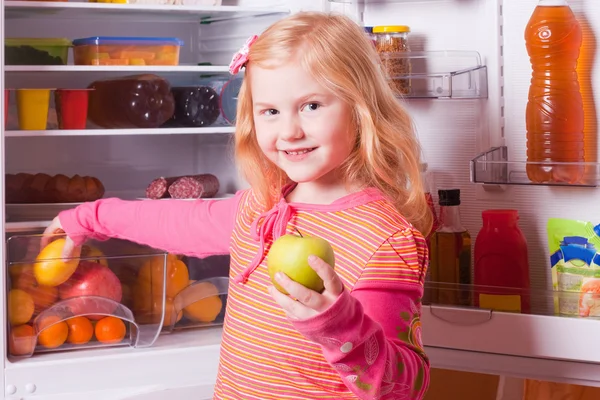 Meisje met voedsel op achtergrond koelkast — Stockfoto