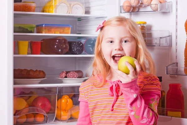 Meisje met voedsel op achtergrond koelkast — Stockfoto