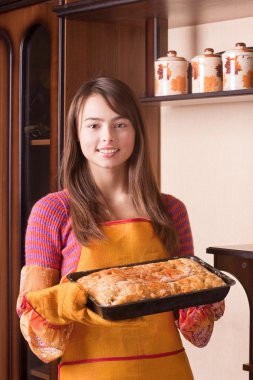 Beautiful girl with cake in kitchen clipart