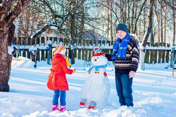 Elderly men and little girl with snowmen — Stock Photo, Image