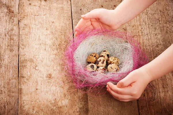 Πασχαλινά αυγά στα χέρια των παιδιών σε ξύλινα φόντο — Φωτογραφία Αρχείου
