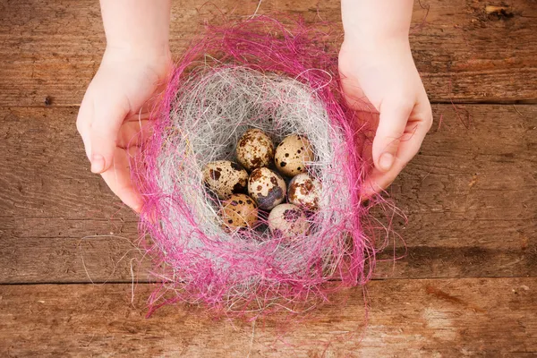 Ovos de Páscoa em mãos de crianças em fundo de madeira — Fotografia de Stock