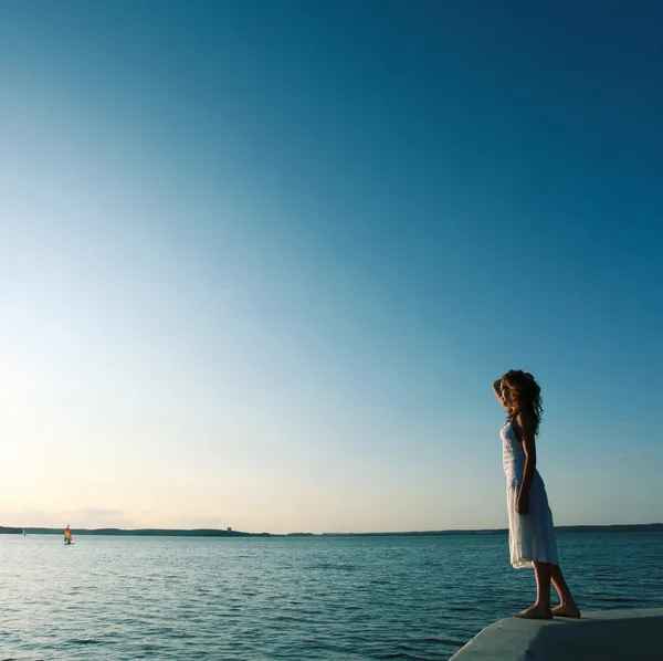 Beautiful girl standing on the shore waiting for a sailboat — Stock Photo, Image