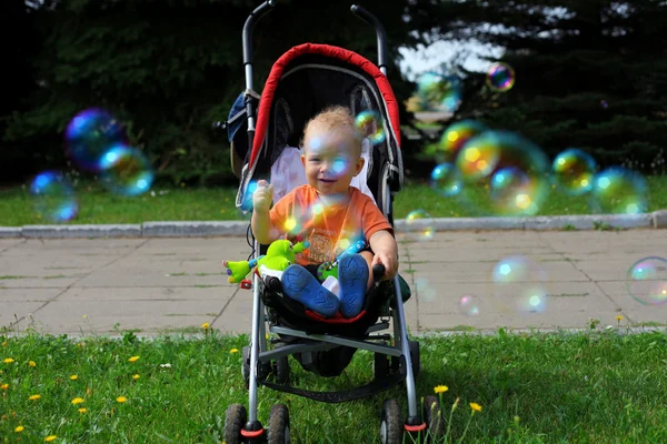 Kleiner glücklicher Junge mit Kinderwagen in — Stockfoto