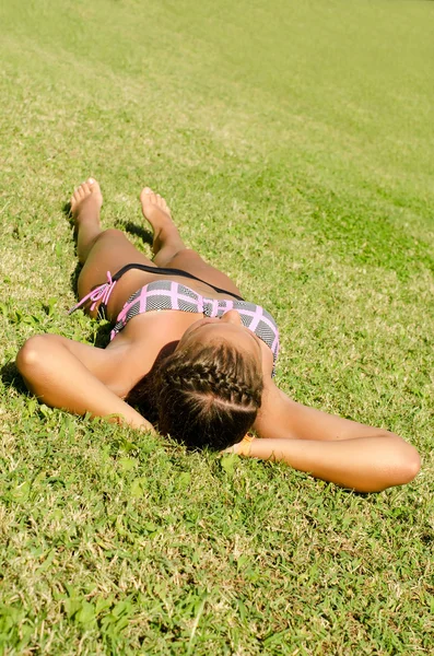 Das junge Mädchen im Bikini liegt auf einem Gras — Stockfoto