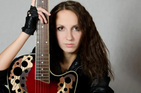 Красивая девушка в кожаной куртке с гитарой — стоковое фото