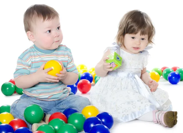 Το μικρό κορίτσι και αγόρι παίζει πολυ-χρωματιστές μπάλες απομονωθεί — Φωτογραφία Αρχείου