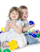 A kis lány és egy fiú játszik elszigetelt multi-színes labdák