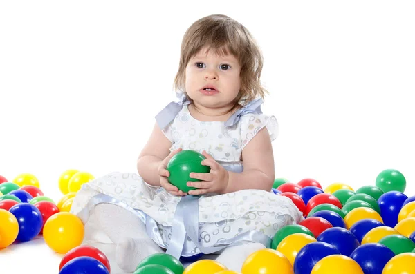 Het kleine meisje speelt multi gekleurde ballen — Stockfoto