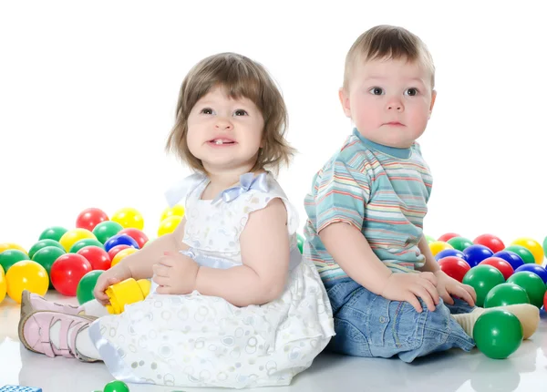 Den lilla flickan och pojken spelar flerfärgade bollar isolerade — Stockfoto