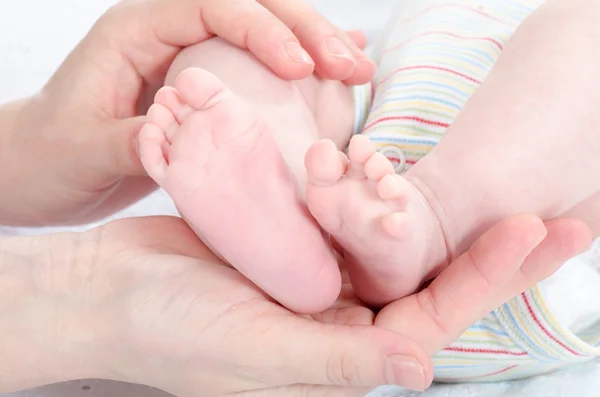 Mother's hands holding baby's feet — Stock Photo, Image