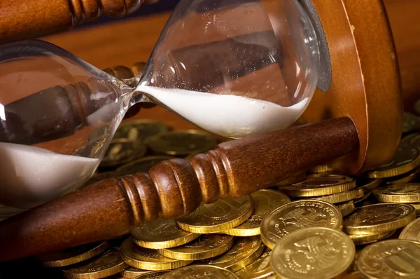 Sanduhr und Münze auf Holztisch — Stockfoto